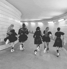 a black and white photo of a group of girls running