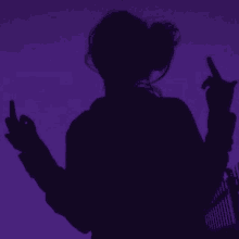 a silhouette of a woman giving the middle finger against a purple background .