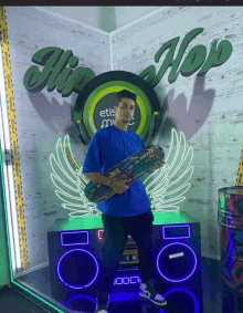 a man holding a skateboard stands in front of a sign that says hip hop