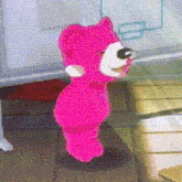 a pink teddy bear is standing on a table in a room