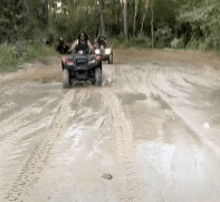 a group of people are riding atvs down a dirt road .