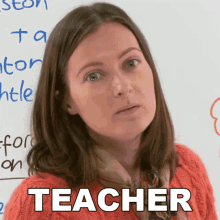 a woman with a scarf around her neck is standing in front of a white board with the word teacher written on it