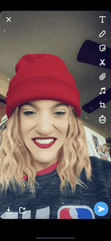 a woman wearing a red beanie and red lipstick smiles for a photo