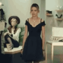 a woman in a black dress is standing next to a mannequin