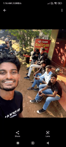 a group of young men are sitting on the ground in front of a sign that says ' avenu ' on it