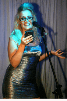 a woman singing into a microphone while holding a cellphone