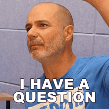 a bald man with a beard wearing a blue shirt that says i have a question