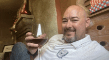 a man in a white shirt is holding a glass of wine and smiling