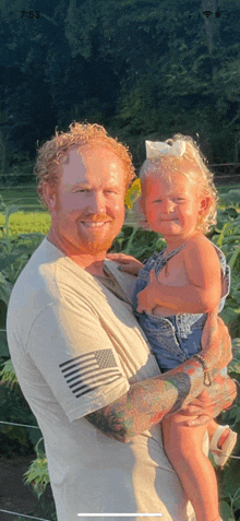 a man is holding a little girl in his arms in a field .