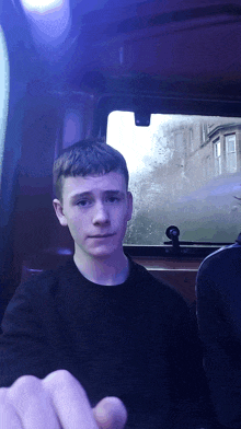 a young man in a black shirt is sitting in a bus