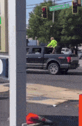 a man in a neon green shirt sits in the back of a truck under a sign that says lingberg dr.