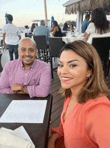 a man and a woman sit at a table with a menu on the table