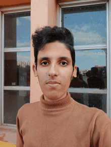 a young man taking a selfie in front of a window with a reflection of a building in it