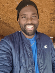 a man wearing a blue shirt and a black hat is smiling