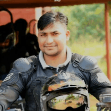 a man wearing a helmet and a jacket with the letter b on it is sitting on a motorcycle