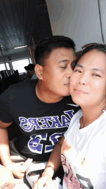 a man is kissing a woman on the cheek while wearing a shirt that says ' vikings ' on it