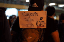 a man wearing a black adidas hat is holding a sign in a foreign language