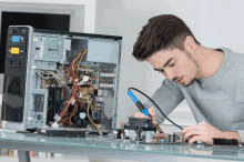 a man is working on a computer with a soldering iron in front of it