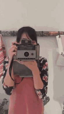 a woman is taking a picture of herself with an old polaroid camera