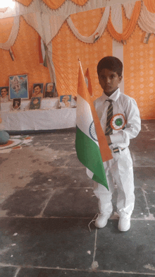 a boy in a white uniform holds a flag in front of a table with pictures on it