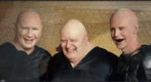 three bald men are posing for a photo and smiling