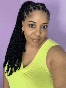 a woman wearing a yellow tank top with braids on her hair