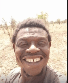 a man with missing teeth is smiling in a field