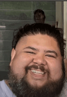 a man with a beard is smiling and has his hair in a bun