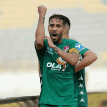 a soccer player in a green ola energy jersey celebrates