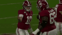 a group of football players are standing on a field and one of them has the number 10 on his jersey .