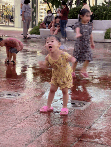 a little girl in a yellow dress stands in a puddle of water