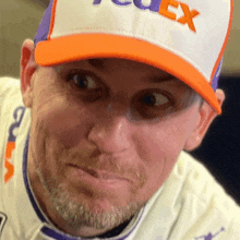 a man wearing a fedex hat makes a face