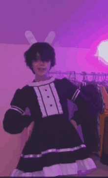 a person wearing bunny ears and a maid dress is standing in front of a purple wall .