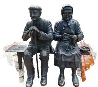 a statue of an elderly couple sits on a bench