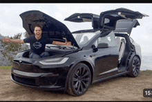 a man stands in front of a black tesla model x