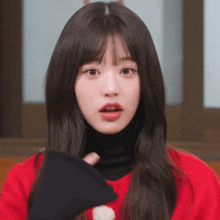 a close up of a young woman wearing a red sweater and black turtleneck .