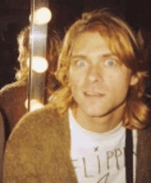 a man with long red hair is standing in front of a mirror wearing a flip shirt .