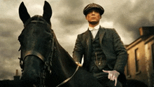 a man in a suit is riding a black horse and pointing at the camera .