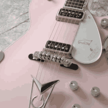 a close up of a pink electric guitar with the word gretsch on the back