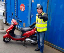 a man standing next to a red scooter with a stop sign behind him