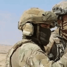 a soldier wearing a mask and a helmet is talking to another soldier .