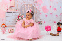 a little girl in a pink dress sits in front of a fireplace with balloons and flowers