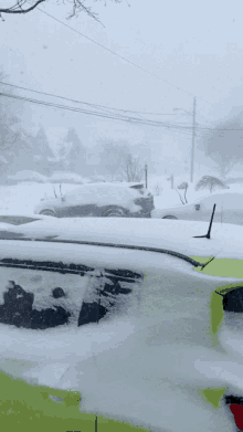 a yellow car is covered in snow and a black car is covered in snow