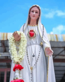 a statue of a woman with a rosary around her neck and a heart in her chest