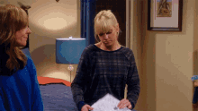 a woman in a plaid shirt holds a piece of paper