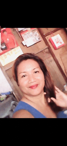 a woman in a blue shirt is taking a selfie in front of a wall with a calendar on it that says 15/12