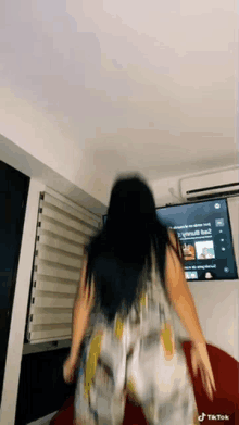 a woman is dancing in front of a television .