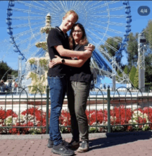 a man and woman are posing for a picture in front of a ferris wheel