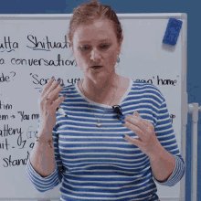 a woman in a blue and white striped shirt stands in front of a white board that says ' atta shitua ' on it