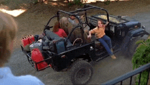 a man is standing next to a jeep with a woman sitting in the back seat .